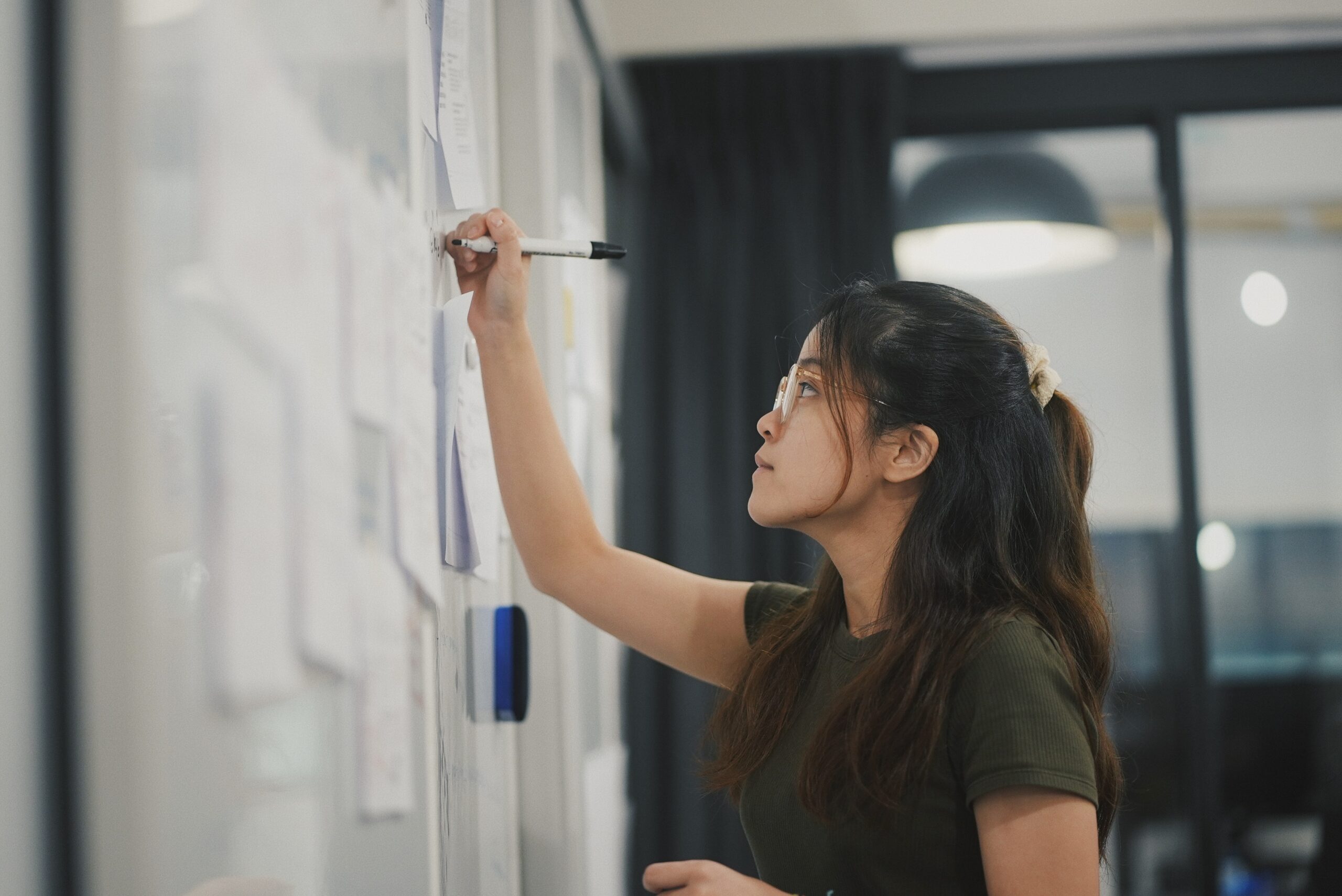 A woman is writing notes on whiteboard image